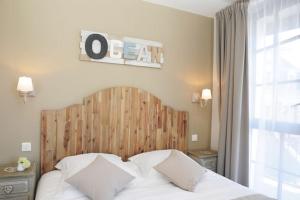 a bedroom with a bed with a wooden head board at Hôtel Restaurant Corto Maltese in Le Palais