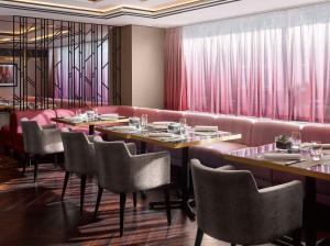a restaurant with tables and chairs and pink curtains at InterContinental Sofia by IHG in Sofia