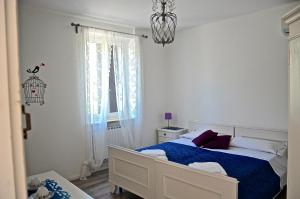 biała sypialnia z łóżkiem i oknem w obiekcie Corte del Garda Home w mieście Castelnuovo del Garda