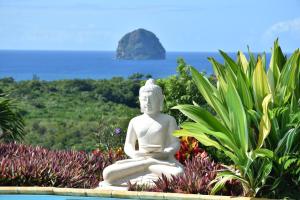 una statua seduta in un giardino con l'oceano sullo sfondo di TI coin de paradis Frangipanier a Le Diamant