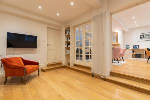 a living room with a television and a chair at ALTIDO Stylish 3 bed mews house with patio in Marylebone in London