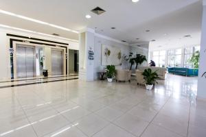 um lobby com piso de azulejos brancos e plantas nele em Di Giulio Hotel em São José dos Campos
