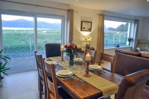 a dining room with a wooden table with flowers and candles at Lurach House in Port Appin