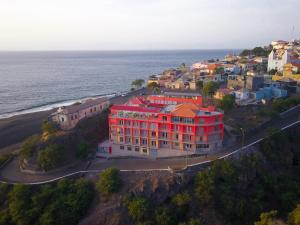 czerwony budynek na wzgórzu nad oceanem w obiekcie Hotel Ocean View & Restaurante Seafood w mieście São Filipe