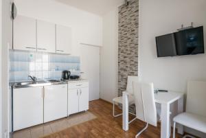 a kitchen with white cabinets and a table and a tv at Villa Voinic 2 in Cavtat