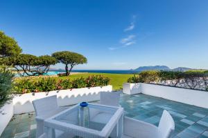 un patio con mesa, sillas y el océano en Hotel Luna Lughente, en Olbia