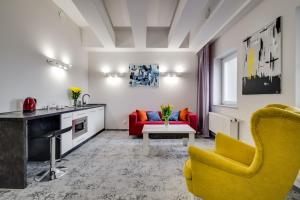 a living room with a yellow chair and a red couch at SAVOY Mariacka Apartments in Katowice