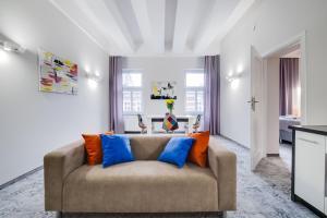 カトヴィツェにあるSAVOY Mariacka Apartmentsのリビングルーム(青とオレンジの枕が付いたソファ付)