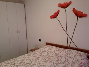 een slaapkamer met twee rode bloemen aan de muur bij Morbegno house in Morbegno