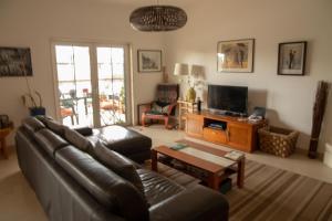 a living room with a leather couch and a tv at Oak Tree Guest House in Azeitao