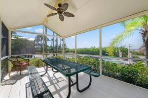 a screened porch with a table and chairs and a fan at Caribbean Beach Club in Fort Myers Beach