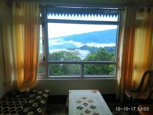 a large window with a view of a mountain at Vamoose Cosynook Homestay in Takdāh