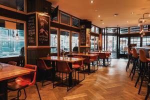 ein Restaurant mit Holztischen und -stühlen und Fenstern in der Unterkunft Hotel Corner House in Amsterdam