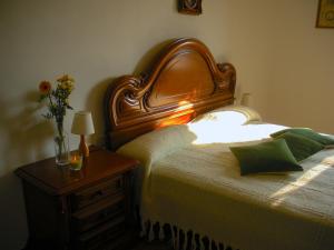 a bed with a wooden headboard and a table with a lamp at Cascina tra i vigneti a Nizza Monferrato in Nizza Monferrato