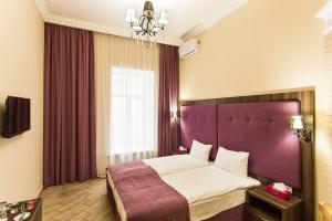 a bedroom with a large bed with a purple headboard at Hotel Baron in Odesa