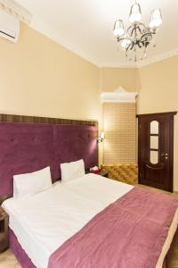 a bedroom with a large bed with a purple headboard at Hotel Baron in Odesa