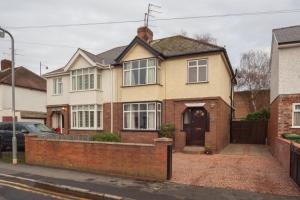 a house with a brick fence in front of it at Goldcrest House by RentMyHouse in Hereford