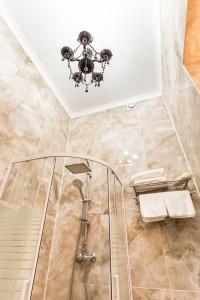 a bathroom with a shower and a chandelier at Hotel Baron in Odesa