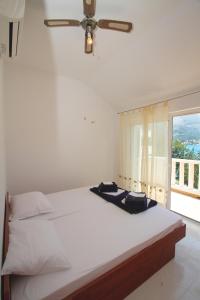 a white bed with a ceiling fan and a window at Villa on the Sea Rock in Slano