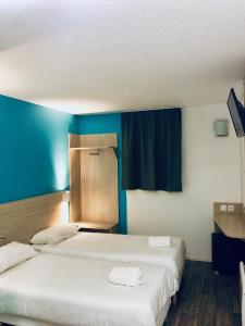 deux lits dans une chambre aux murs bleus dans l'établissement Hôtel du stade ex Kyriad Direct Lille Est Stade Pierre Mauroy, à Villeneuve d'Ascq