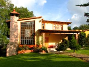 ein kleines Haus mit einem grünen Rasen davor in der Unterkunft Cabañas Lupita 31 in Mazamitla