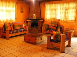 a living room with two chairs and a fireplace at Cabañas Lupita 31 in Mazamitla