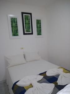 una camera da letto con un letto bianco con due finestre di Flat Porto a Porto De Galinhas