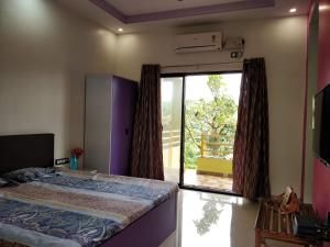 a bedroom with a bed and a sliding glass door at Ushakal in Dapoli