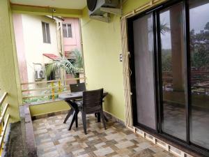 a table and chair on a balcony with a window at Ushakal in Dapoli