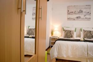 a bedroom with two beds and a mirror at a Vue Guesthouse in Somerset West