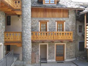 una vecchia casa in pietra con balconi in legno e ringhiere in legno di Maison Chante Lune a Introd