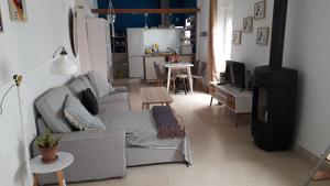 uma sala de estar com um sofá cinzento e uma televisão em La Tia Vinagre em Vejer de la Frontera