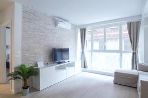 un salon avec une télévision sur un mur en briques dans l'établissement Marconi Apartments, à Bologne