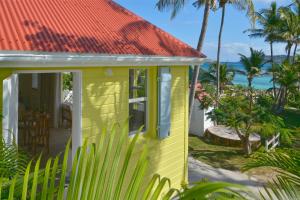 Les Ilets De La Plage في غوستافي: منزل أصفر بسقف برتقالي على الشاطئ