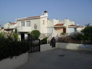 uma grande casa branca com um portão em frente em Villa Theodora em Pafos