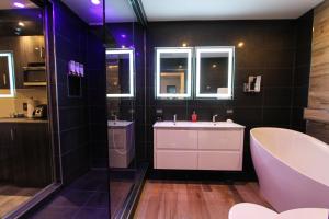a bathroom with a tub and a sink and a tub and a bath tub at Hôtel Saint-Germain Rimouski in Rimouski