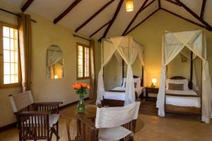 a bedroom with two beds and a table and chairs at Kili Villa Kilimanjaro Luxury Retreat in Arusha