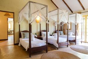 a bedroom with four canopy beds with white sheets at Kili Villa Kilimanjaro Luxury Retreat in Arusha