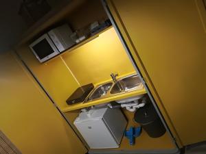 a small yellow kitchen with a sink and a counter at Postaláda vendégház in Salföld