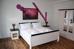 a bedroom with a white bed with a pink painting on the wall at Apartments Schöneberg in Berlin