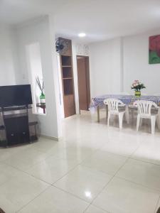 a living room with a table and chairs and a tv at Confortável 2 Quartos Castanheiras in Guarapari