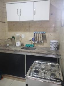 a kitchen counter with a stove and a sink at Confortável 2 Quartos Castanheiras in Guarapari