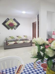 a living room with a couch and a vase of flowers at Confortável 2 Quartos Castanheiras in Guarapari