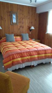 Cama grande en habitación con paredes de madera en Piuké en San Carlos de Bariloche