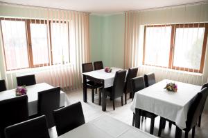 a restaurant with white tables and chairs and windows at Step Inn in Alba Iulia