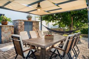 a patio with a wooden table with chairs and a hammock at Alexander villa in Perdika