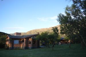 a house in a field with a mountain in the background at Complejo Arlington Village in Cortaderas