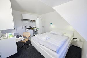 ein weißes Schlafzimmer mit einem Bett und einem Schreibtisch in der Unterkunft Aparthotel Jonas in Bremen