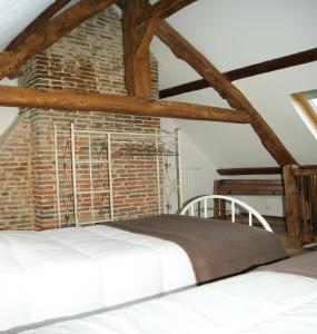 Gîtes Normands de charme les châtaigniers في Bretteville-du-Grand Caux: سرير في غرفة بجدار من الطوب
