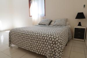a bedroom with a bed with a black and white comforter at T2 Buis de Chine - GOSIER Port-Blanc in Le Gosier
